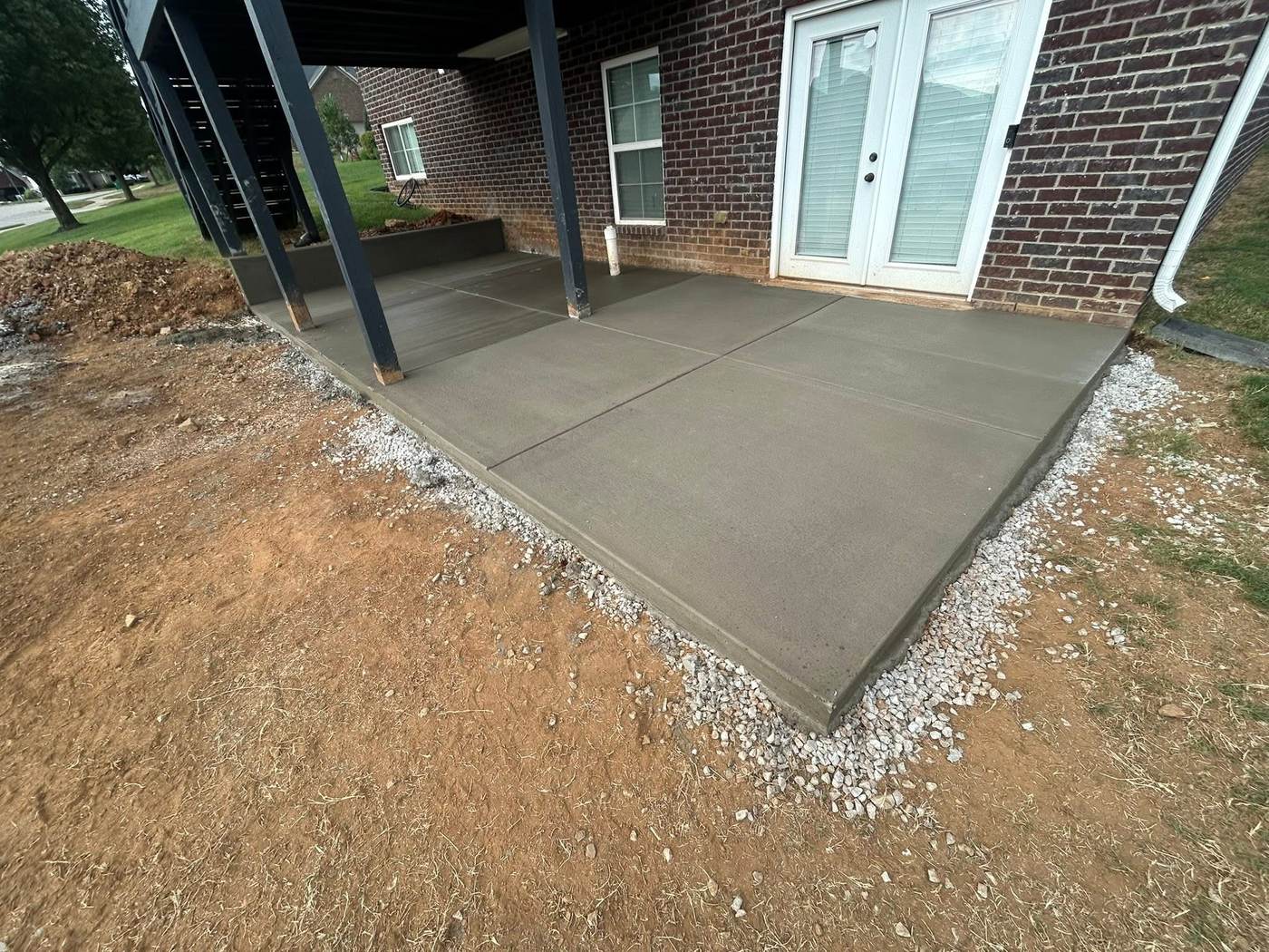 Finished concrete patio beneath a covered porch at a brick home